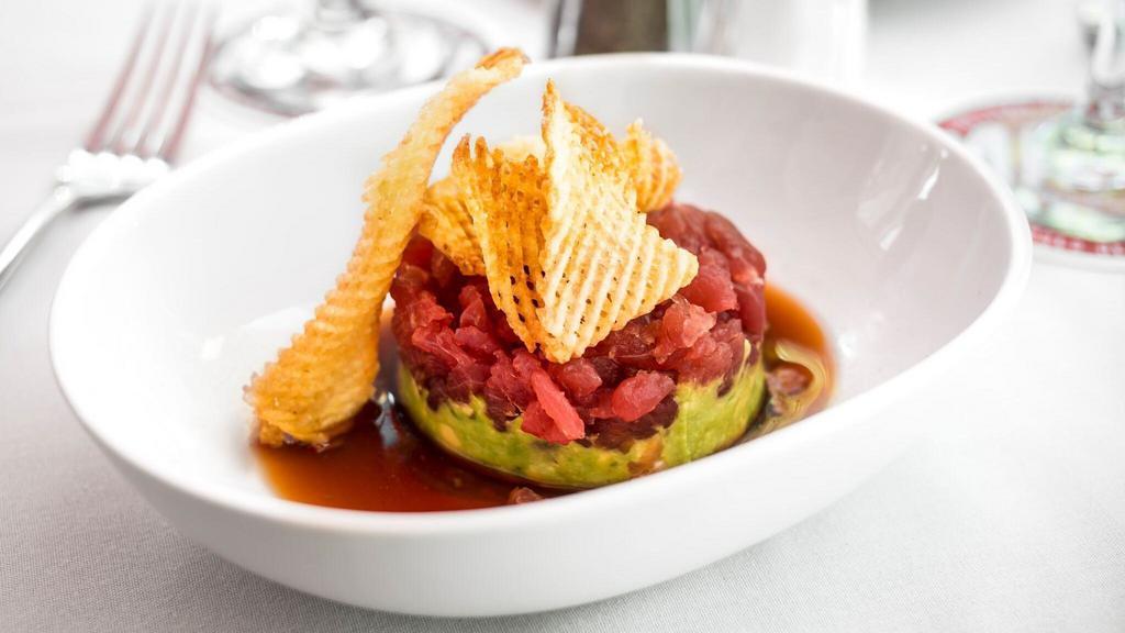 Yellowfin Tuna Tartare · A true delicacy made to order. Hand-cut sushi grade yellowfin tuna placed on top of crushed avocado served with ponzu dipping sauce and potato gaufrettes.