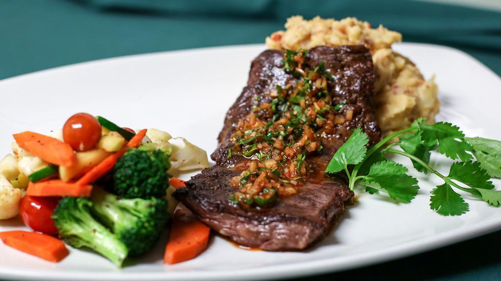 Skirt Steak Perfecto · Nine ounces grilled skirt steak (beautifully marinated overnight) topped with a chimichurri-cilantro sauce. Served with chorizo mashed potatoes, and sautéed seasonal veggies in garlic and olive oil.