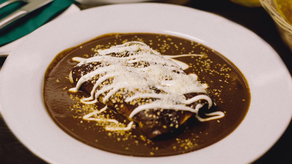 Enchiladas De Mole · Corn tortillas filled with roasted chicken, cheese, topped with our authentic mole sauce, served with rice and beans.