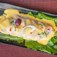 Papa A La Huancaina · Boiled potato on a bed of lettuce with spicy and creamy dressing.
