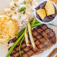 Churrasco · Grilled steak with rice, beans, and salad. / Carne de res con arroz frijoles y ensalada rusa.
