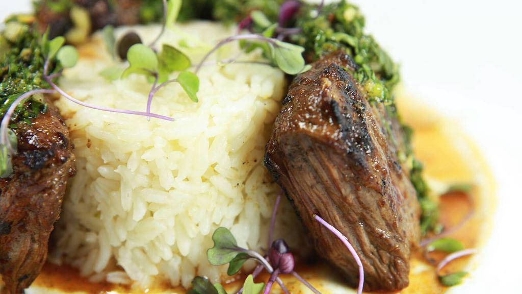 Carne Asada · 8 oz. skirt steak marinated with Mexican spices, served with white rice & black beans. Topped with a red wine reduction & chimichurri salsa. Gluten-Free.