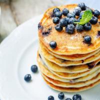 Blueberry Buttermilk Pancakes · Three perfectly fluffy blueberry pancakes served with a side of butter and syrup.