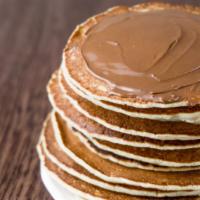 Nutella Buttermilk Pancakes · Three perfectly fluffy nutella pancakes served with a side of butter and syrup.