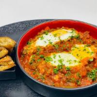 Shakshuka · Poached eggs cooked in a tomato and pepper sauce served with fresh pita, tahini, fresh cut v...