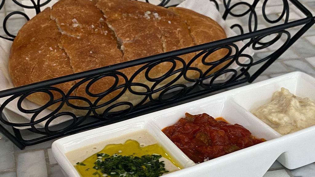 Accent Bread · Freshly baked frena bread in a taboon oven served with a three-dip, matbucha, tahini, and eggplant spread.