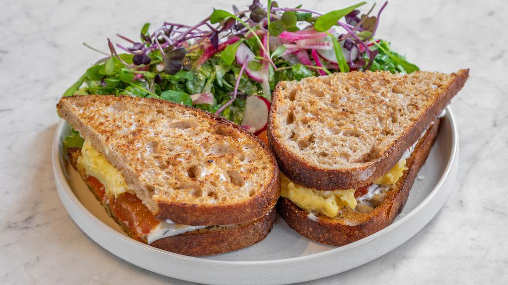 Best Breakfast Sandwich In The Lower East Side · Our house-made sourdough bread toasted, scrambled egg, cheddar cheese, roasted tomato, and garlic herb mayo. Make it vegan with our vegan scrambled eggs!