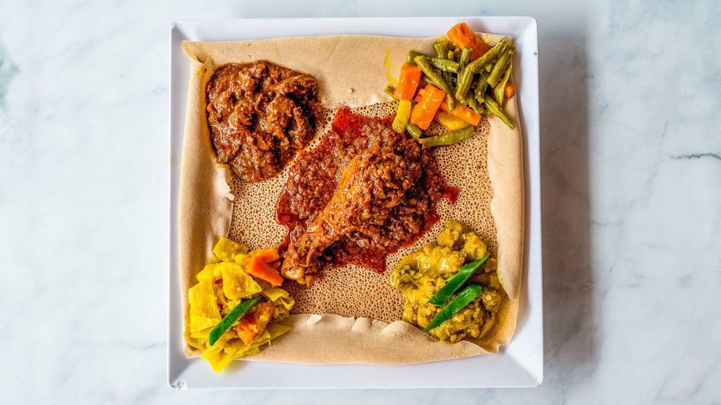 Meat Combo · Doro wat (chicken stew spicy), tibs wat (beef stew spicy), yesiga alicha (beef stew mild), and with two side vegetables.