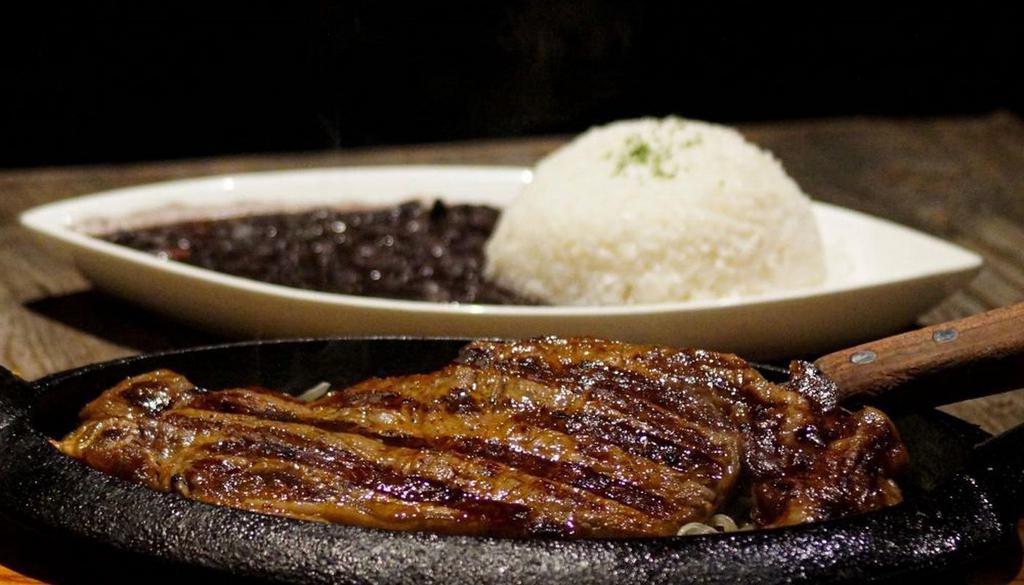 Bistec De Palomilla · Grilled pounded sirloin steak,  sautéed onions, rice and beans