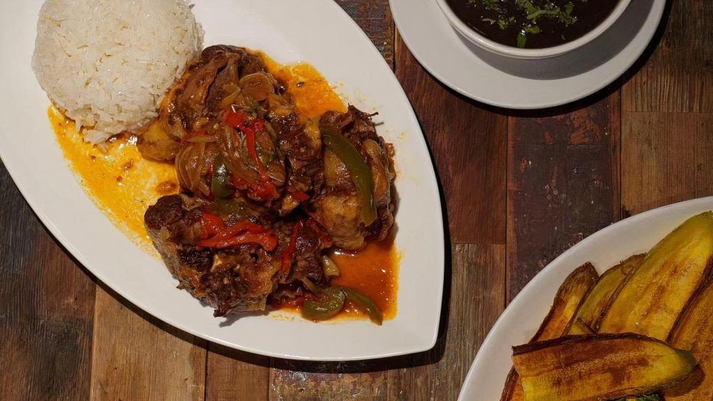 Rabo Encendido · Braised Oxtail in tomato red wine sauce, peppers, onions, cilantro, served with rice and beans