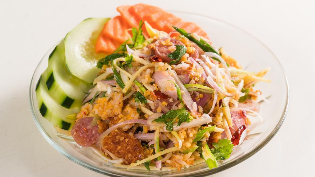 Yum Nam Khao Todd · Spicy. Snack sized. Laotian influence rice salad with crispy rice, grated coconut, and fermented pork sausage, tossed with ginger, peanut, dried chili, mint, basil, lime juice, and fish sauce.
