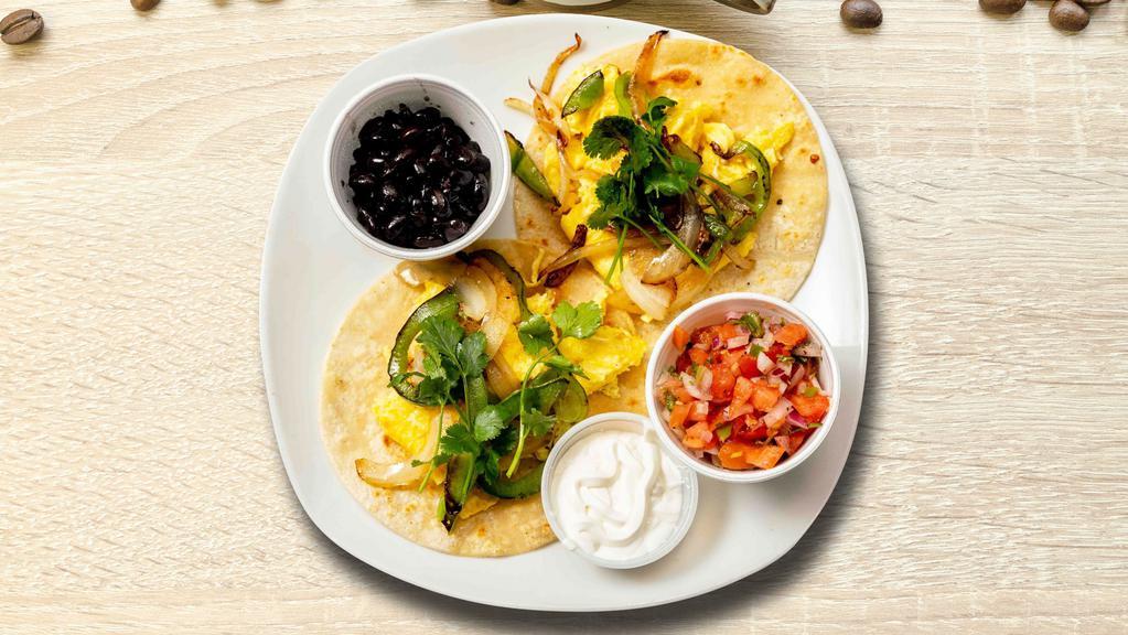 Huevos Rancheros Scramble · Lightly fried eggs served on a warm tortilla and topped with salsa, tomatoes, chili peppers, onions, cilantro, guacamole, black beans, and sour cream.