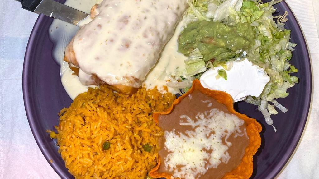 La Changa · 12-inch flour tortilla folded and deep fried or soft filled with refried beans  your choice of shredded chicken or ground beef, topped with nacho cheese and burrito sauce. Served with lettuce, sour cream, guacamole and rice.