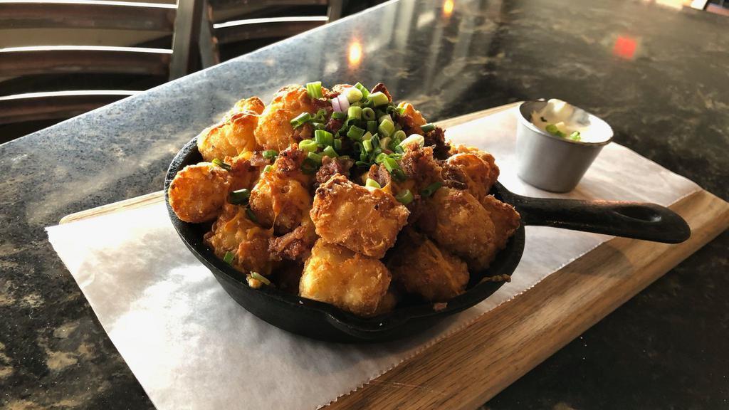 Loaded Tots · Tots smothered in bacon, cheddar cheese, and topped with green onions and a side of sour cream
