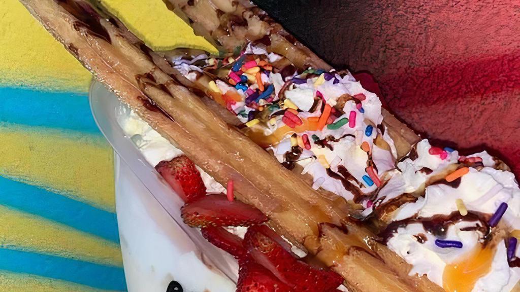 Churro Split Sundae · This sundae stars two hot, fresh churros to compliment your three scoops of ice cream.  Comes drizzled with caramel sauce and chocolate sauce, and is also topped with rainbow sprinkles.