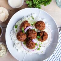 Falafel Over Rice · Delectable rice platter served with chickpea falafel, lettuce, and tomatoes. Comes with whit...
