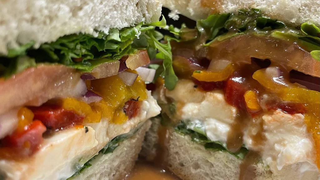 Burrata Sandwich · Black truffle burrata sliced and served on a baguette with house-made maple balsamic vinaigrette, roasted red and yellow peppers, red onion, arugula, and tomatoes. Served with your choice of fries or a salad.