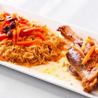 Uzbeki Qabuli Pulao · Braised lamb shank served over a bed of rice and garnished with sweet raisins and carrots. T...
