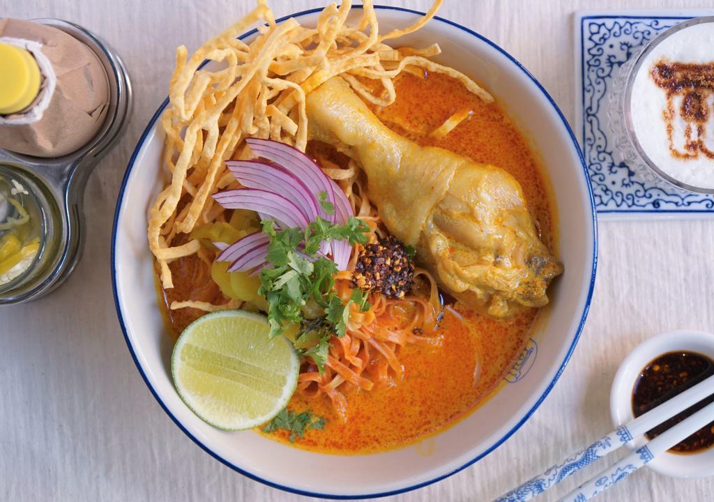 Chicken Khao Soi · Northern-style curry soup served with egg noodles along with a tender chicken leg, shallots, pickled radish, chili oil and topped with crispy egg noodles.