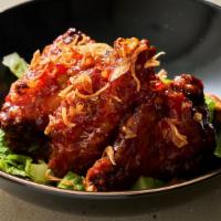 Peek Gai Mak Khamin Tord · Deep fried chicken wings marinated turmeric topped with fried shallot, spicy and sweet sauce.