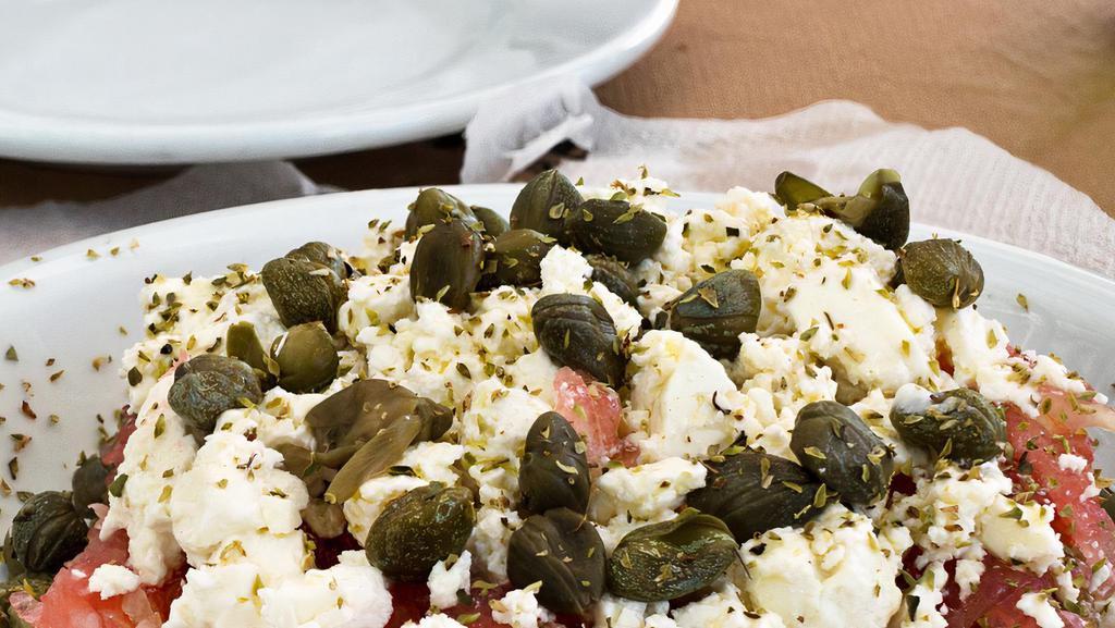 Dakos Traditional Cretan Salad · Chopped tomatoes, onions, Arahova feta, capers. Topped with traditional Cretan dry bread (Rusks) & flavored with herbs & extra virgin olive oil.