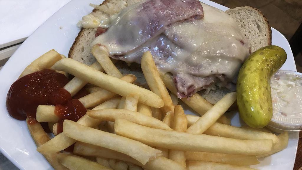 Reuben Sandwich · Corned beef on pastrami and sauerkraut topped with melted Swiss cheese on rye bread. Served with coleslaw and French fries or potato salad.