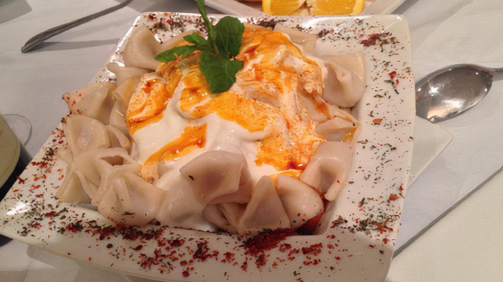 Manti · Traditional Minces Beef Dumplings Served With Garlic Yogurt and Tomato Sauce, Herbs With Fresh Mint Leaves.
