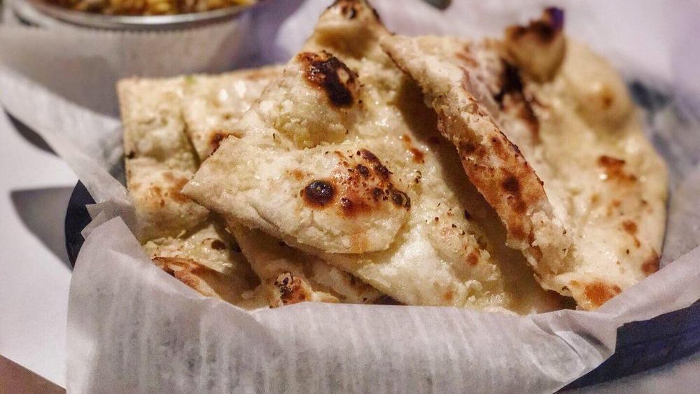 Garlic Naan · Leavened bread baked with garlic and cilantro laced with butter.