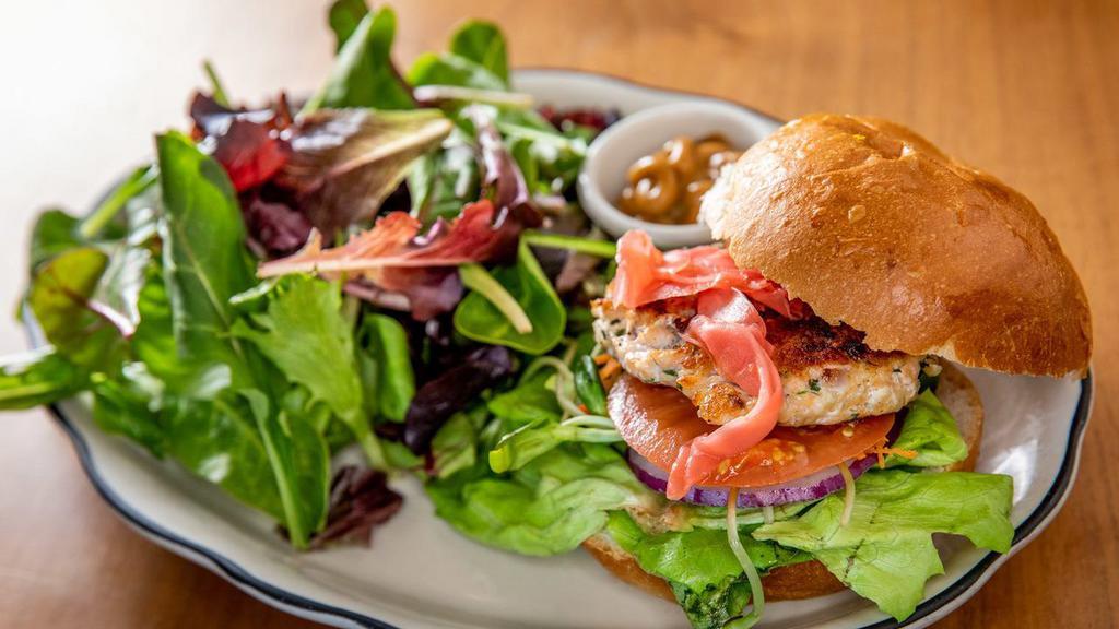 Salmon Burger · Fresh Atlantic salmon mixed with diced red onion, parsley, garlic, lettuce, sun flower sprouts, carrots, red onions, pickled ginger, tomatoes, cucumbers, and miso sauce.