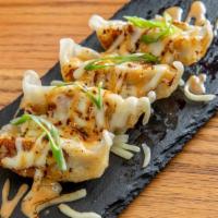 Gyoza · Pan seared chicken, pork, and cabbage with black ginger sauce.