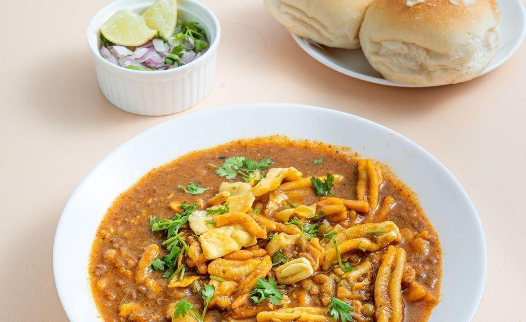 Misal Pav · A spicy lentil (turkish gram) and potato chili served with a side of fresh butter-toasted rolls.  Spice Level: High