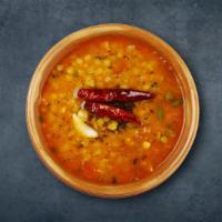Lentil Legacy · Yellow dal cooked in a pot with chilies, onion, spices and herbs. Served with a side of rice.