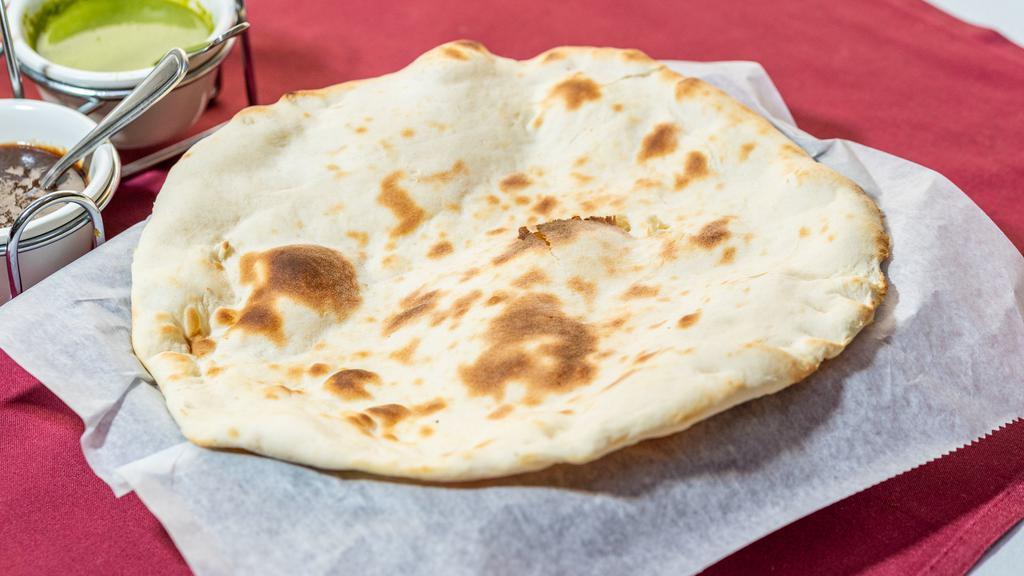 Naan · Teardrop-shaped white bread baked by slapping it quickly on the sides of the tandoor served piping hot with or without butter.