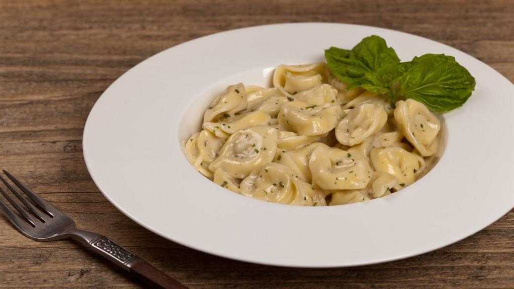 Tortellini Alfredo · Fresh tortellini alfredo with roasted peppers and peas topped with parmesan cheese.