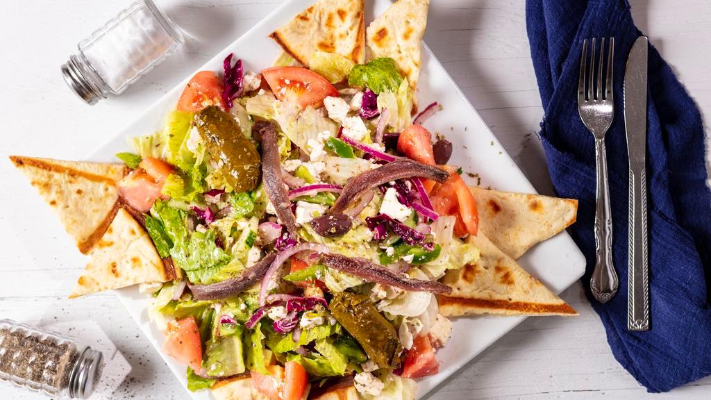 Greek Salad · Crisp lettuce, tomatoes, cucumbers, feta cheese, onions, olives, stuffed grape leaves and anchovies tossed with our delicious Greek dressing and served with pita bread.