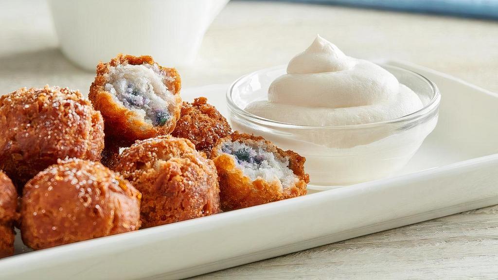 Blueberry Muffin Bites · 8 bite–sized natural blueberry flavored nuggets sprinkled with powdered sugar. Served warm, with a side of whipped cream cheese.