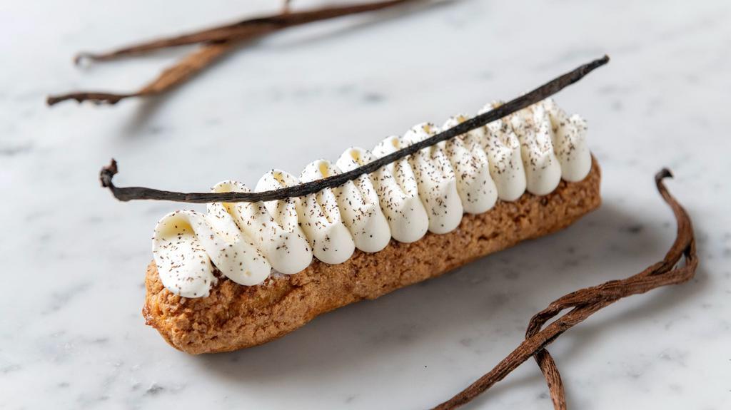 100% Vanilla Eclair · Crunchy choux pastry dough filled with 100% vanilla cream which has been infused with Tahitian vanilla beans for a period of 24 hours, finished with a lightly-sweetened vanilla chantilly, pieces of almond dough, and sprinkled with vanilla bean powder