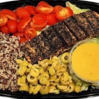 Salmon Quinoa Power Meal · A delicious meal with Greens, Cherry tomatoes, Quinoa, Green Olives, topped with a white win...