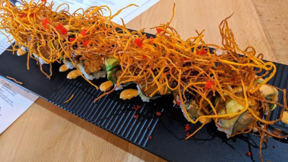 Akino Roll · Inside spicy kani and cucumber topped with eel, avocado, tobiko, sweet potato crisps, spicy mayonnaise, and eel sauce.