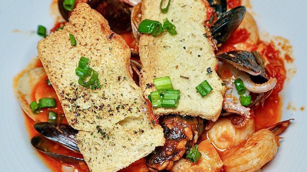 Cioppino · The San Francisco Favorite; clams, mussels, calamari, shrimp, scallops, and fresh fish. Sautéed with garlic, fennel, and shallots. Simmered in white wine, fumet, and tomato broth. Finished with garlic crostinis over linguine.