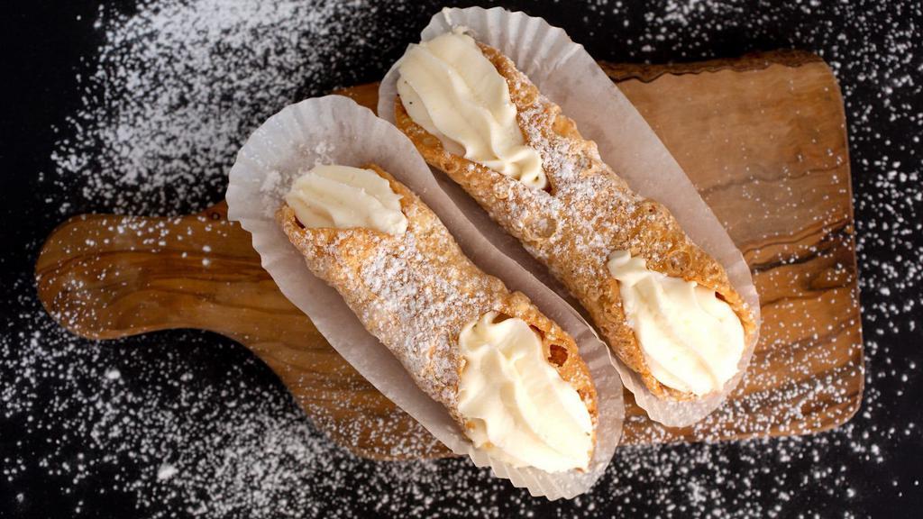 Cannoli · Delicate, fried pastry dough tubes, filled with sweet, creamy ricotta and a dusting of powdered sugar.