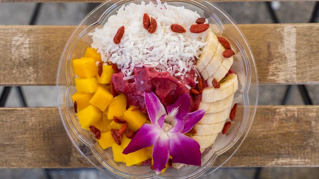 Pitaya Bowl · Soy milk with pitaya, banana, and strawberries as base. On top coconut flakes, mango, banana and edible flower.