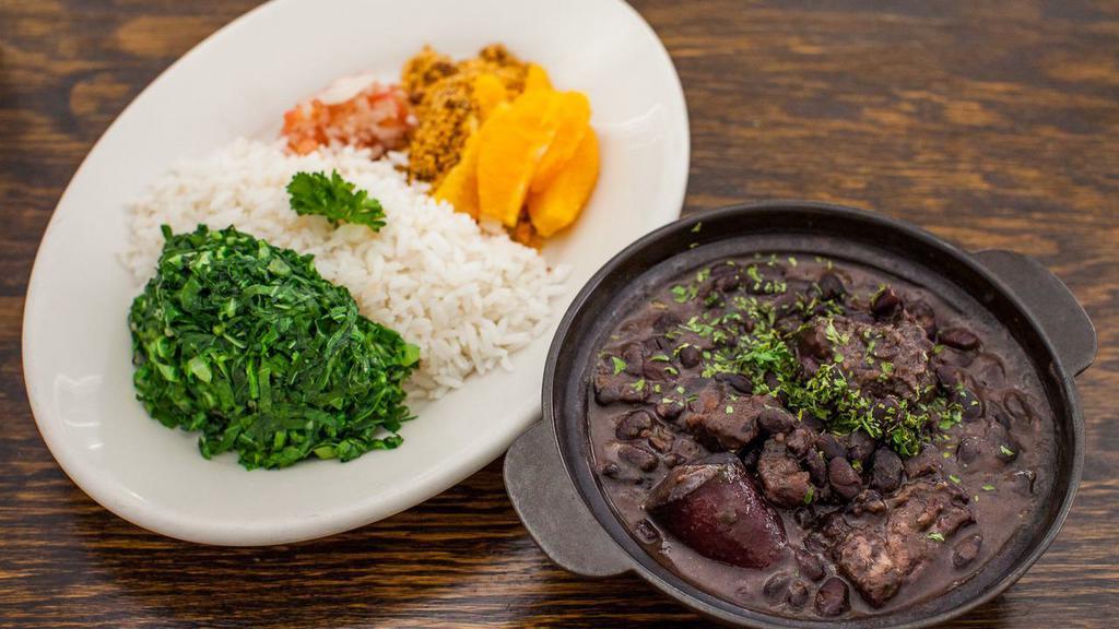 Feijoada · Brazilian national dish: black bean stew with prime meats served with white rice, fresh oranges, collard greens, farofa and vinaigrette sauce