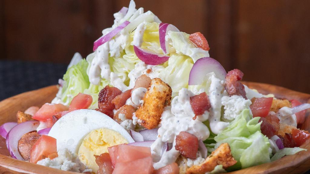Wedge Salad · Large Wedge of Iceberg Lettuce topped with our Creamy Homemade Blue Cheese dressing, Shaved Red Onion, Applewood Smoked Bacon,Diced Tomato, Boiled Egg and House Made Croutons