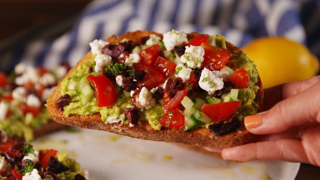 Greek Avocado Toast · Mouthwatering Avocado Toast topped with feta cheese, olives, red onion, sliced cucumber and oregano.