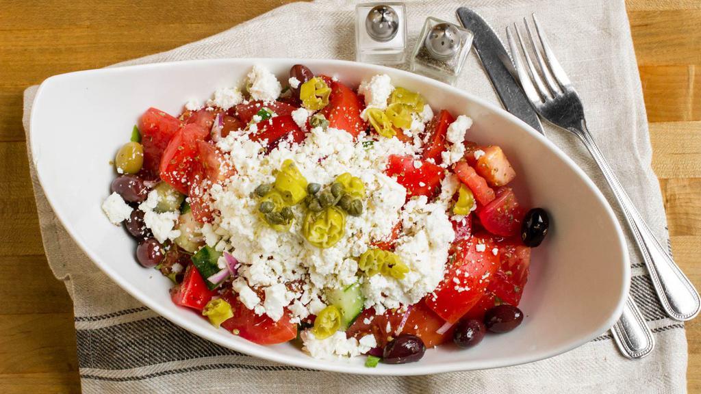 Horiatiki · A traditional Greek salad with lettuce, tomatoes, cucumbers, pepperoncinis onions, capers, olives, feta cheese, extra virgin olive oil and vinegar dressing.