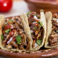 Tacos De Cerdo (Pork Tacos) · Marinated pork, onions, cilantro, and avocado on a fresh made tortilla.