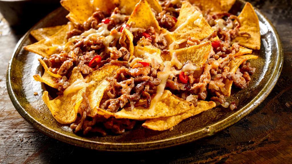 Beef Nachos · Flavorful beef with sautéed onion and peppers and topped with melted cheese loaded onto crispy tortilla chips.