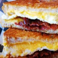 Breakfast Melt · Melted American cheese, bacon and fried eggs on sourdough. Served with home fries