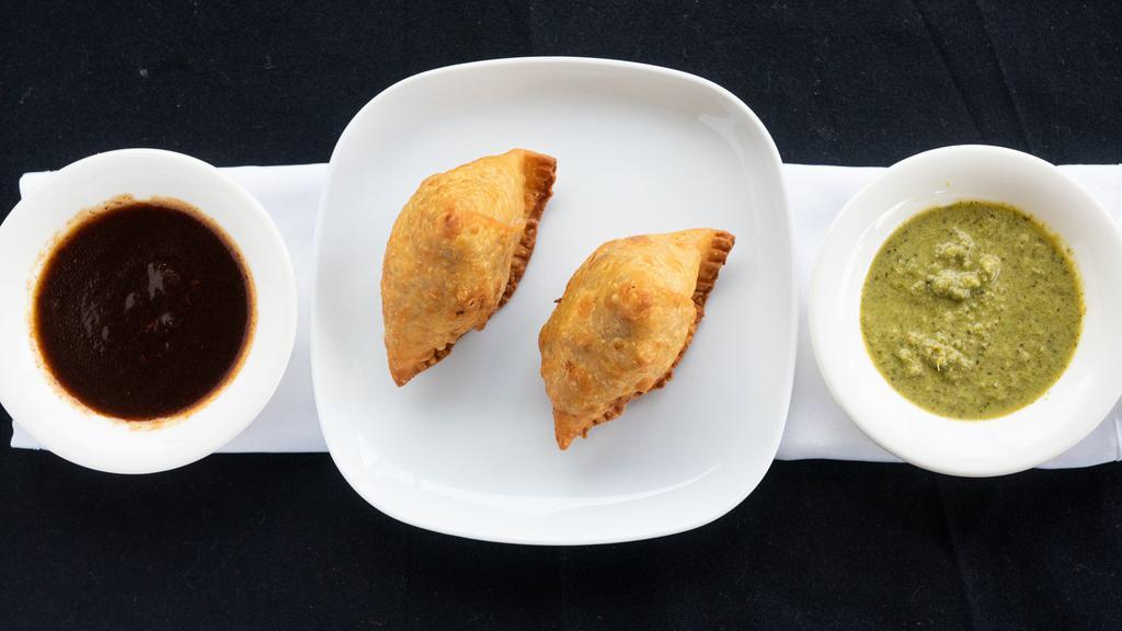 Vegetable Samosa · A crispy pastry stuffed with potatoes and onion fritters.